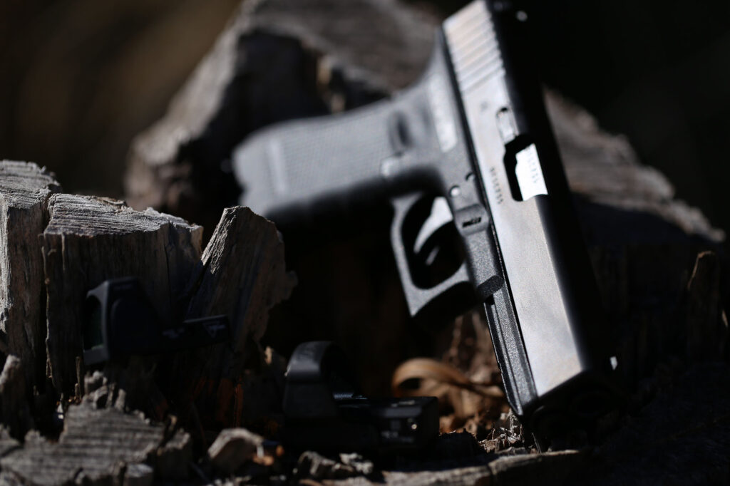 glock in a tree stump with reflex sights